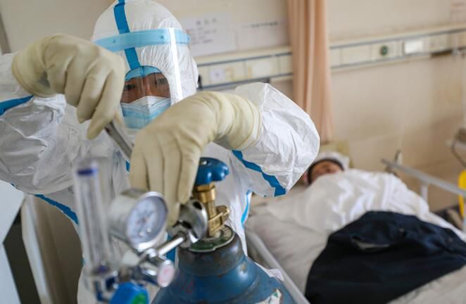 2020年2月16日，武汉红会医院，邓新财在隔离病房换氧气瓶上的流量阀。(陈卓 摄)