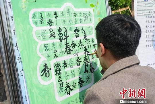 3月21日，在江西理工大学广场，一名学生在“百春图”写“春”。　曾江文 摄