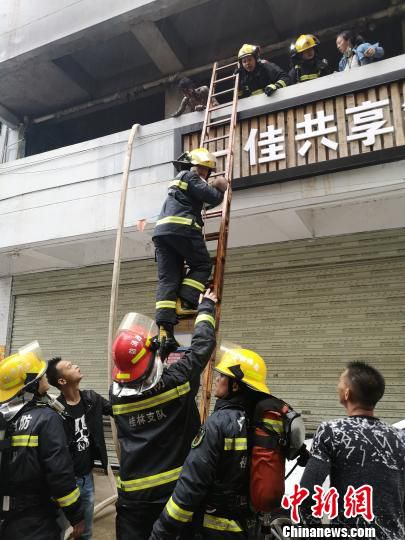 图为消防救援人员正在营救一名被困婴儿。　熊有发 摄