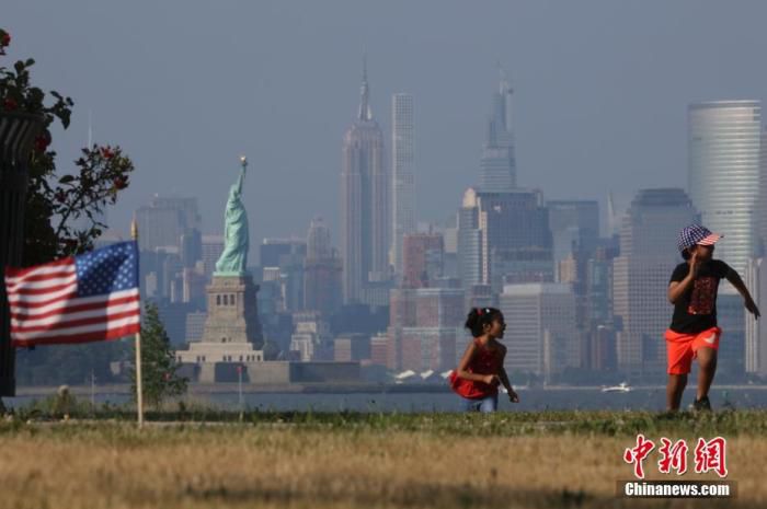 资料图：当地时间7月4日，两名孩童在纽约曼哈顿对岸的海滨草坪上奔跑。中新社记者 廖攀 摄