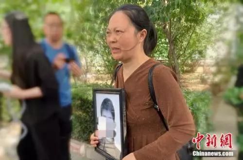 　谢雕母亲带着谢雕的遗照走出法院 中新网 杨雨奇 摄