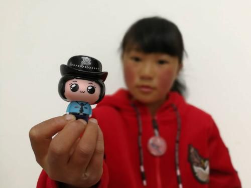 “冰花男孩”姐姐王福美在展示玩偶。中国长安网供图