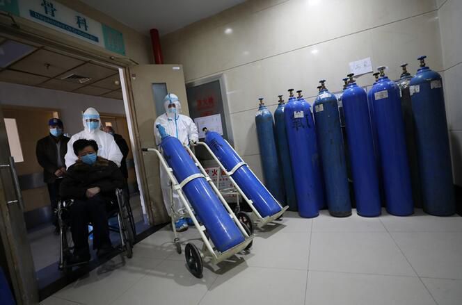 2020年2月16日，武汉红会医院，邓新财在搬运氧气瓶时遇到患者去检查，赶紧让路。(陈卓 摄)