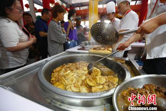 5月16日，亚洲文明巡游和亚洲美食节在北京奥林匹克公园中心区内开幕。图为美食节场馆内，民众正在排队购买京城特色小吃。(完) 富田 摄