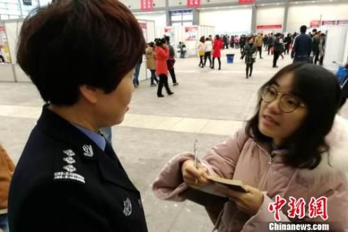 图为民警为招聘会上的大学生讲解户籍新政。　燕武 摄