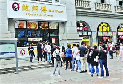 22日中午，江汉路地铁站D出口附近挂着“鲍师傅”招牌的糕点店门前，十几个人正在排队 记者李永刚 摄