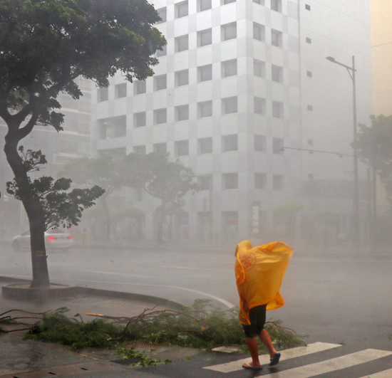 在风雨中行进的那霸市路人(图片来源:朝日新闻)