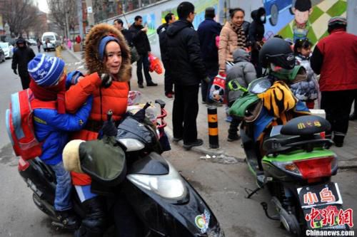 资料图：家长骑电动车把孩子送到学校。<a target='_blank' href='http://www.chinanews.com/' >中新网</a>记者 金硕 摄