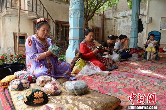 新疆喀什老城一家手工艺品合作社里，妇女们正在制作手工花帽。　勉征 摄