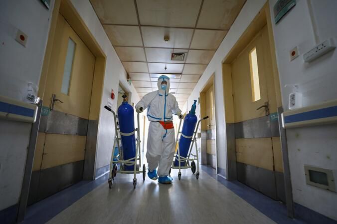 2020年2月16日，武汉红会医院，邓新财用拖车拖着氧气瓶一路小跑送到隔离病区。(陈卓 摄)
