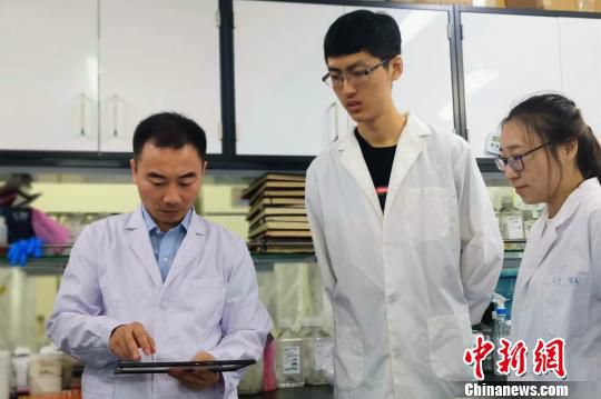 黄志伟教授(左一)在实验室中工作 王琳 摄