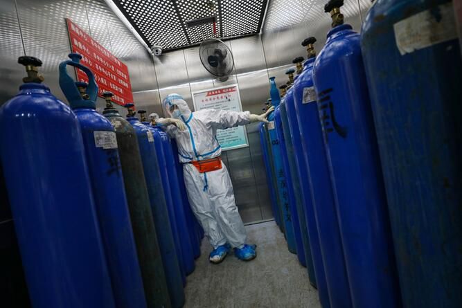 2020年2月16日，武汉红会医院，邓新财在搬运制氧公司刚刚送到的氧气瓶，十几个120斤的氧气瓶运进电梯，邓新财累的靠在瓶罐上。(陈卓 摄)