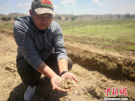 图为王玲崇捧起一撮沙土分析当地的土质条件。　魏建军 摄