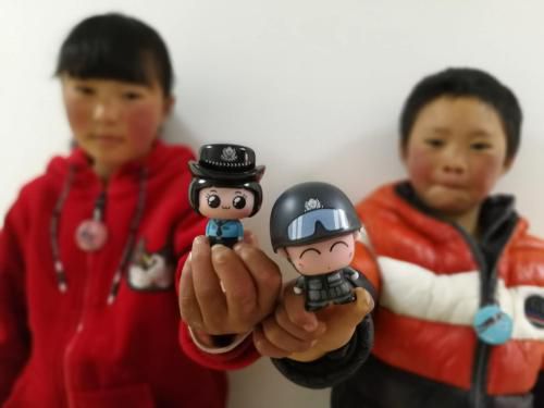 “冰花男孩”王福满和姐姐在展示手中玩偶。中国长安网供图
